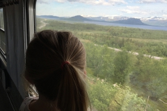 När vi närmar oss Abisko blir Klara stående i tågfönstret och tittar på de snöklädda fjällen